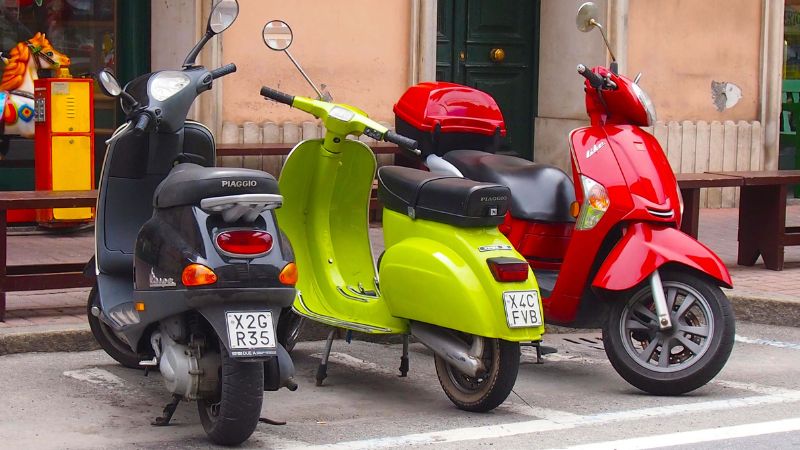 Three colorful Vespas (black, green, red) parked on a Montreal street