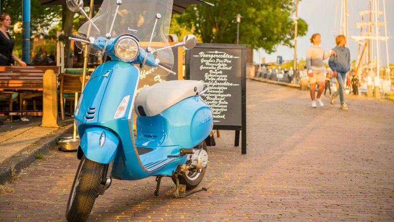 Blue Vespa parked by a cafe at Montreal's Old Port, capturing local charm.
