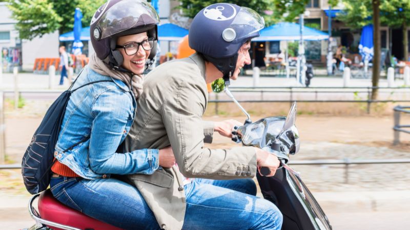 Happy couple riding a Vespa through Montreal's vibrant streets.